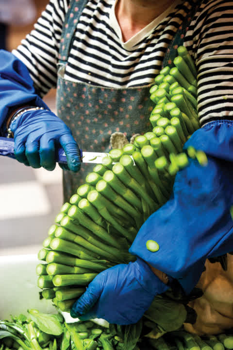 A stallholder is cutting vegetables in Link REIT TKO Market. A stallholder is cutting vegetables in Link REIT TKO Market.